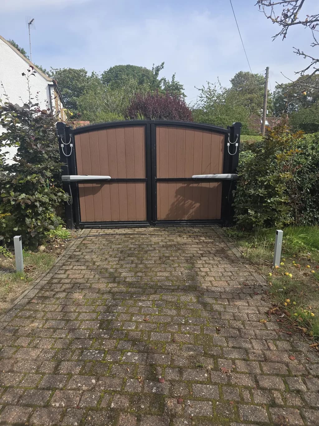 Timber-clad gates on a block-paved residential entrance
