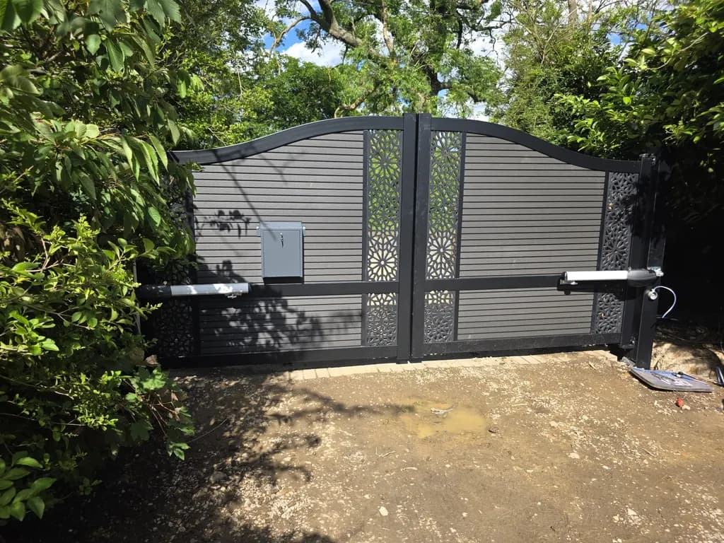 Grey gates with decorative laser-cut inserts at a rural entrance