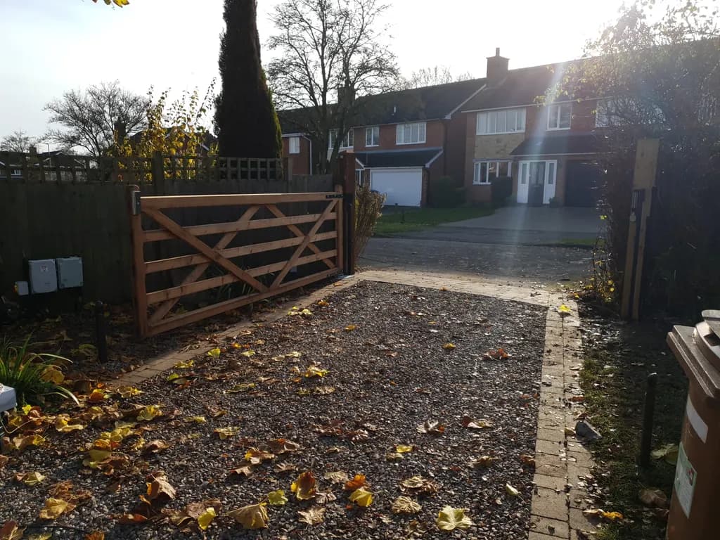 Timber five-bar gate on a gravel driveway in autumn