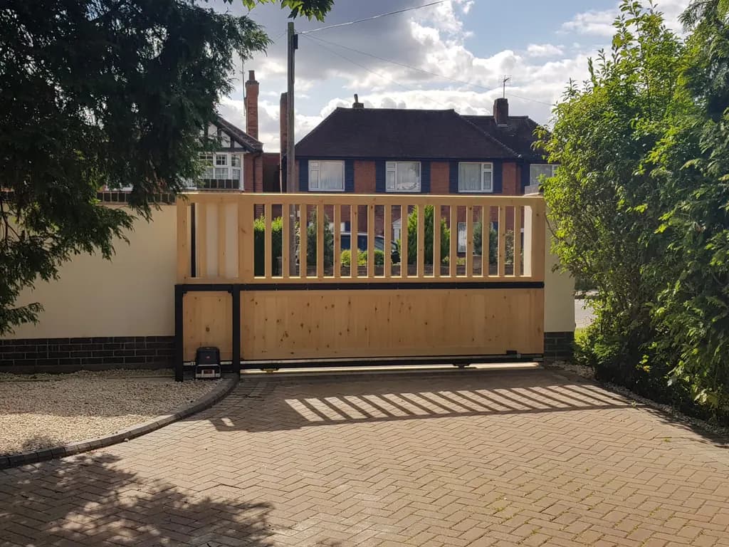 Low timber gate with open top rail across a residential driveway