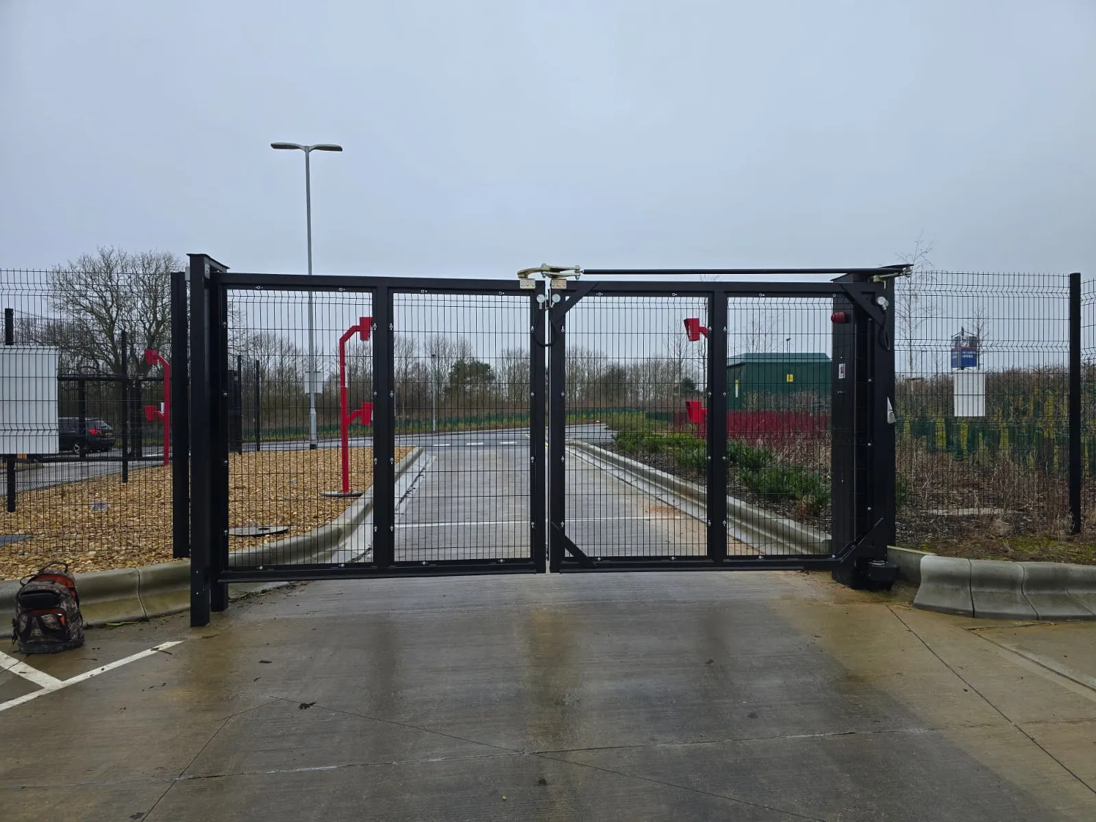 Mesh swing gates with rising bollards and warning beacons at a controlled entrance