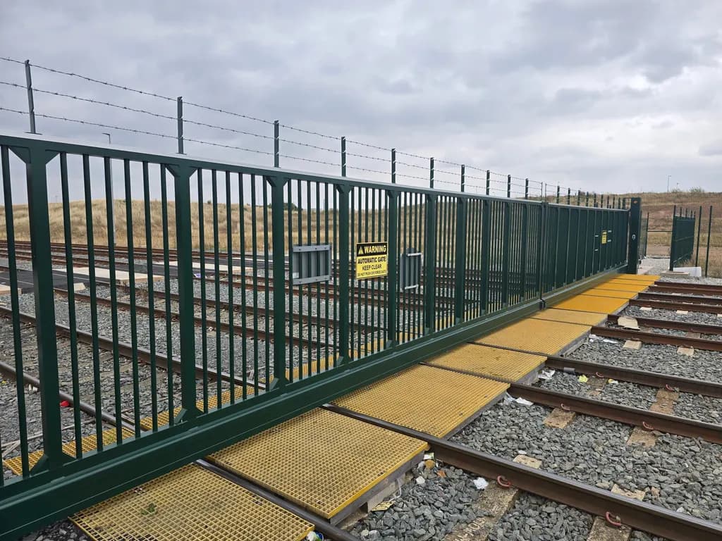 Green palisade sliding gate securing a railway siding