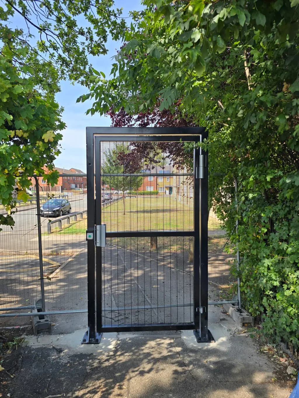 Mesh pedestrian access gate beside a vehicle entrance