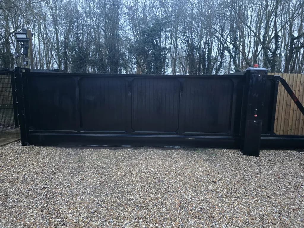 Dark slatted sliding gate on a private gravel drive