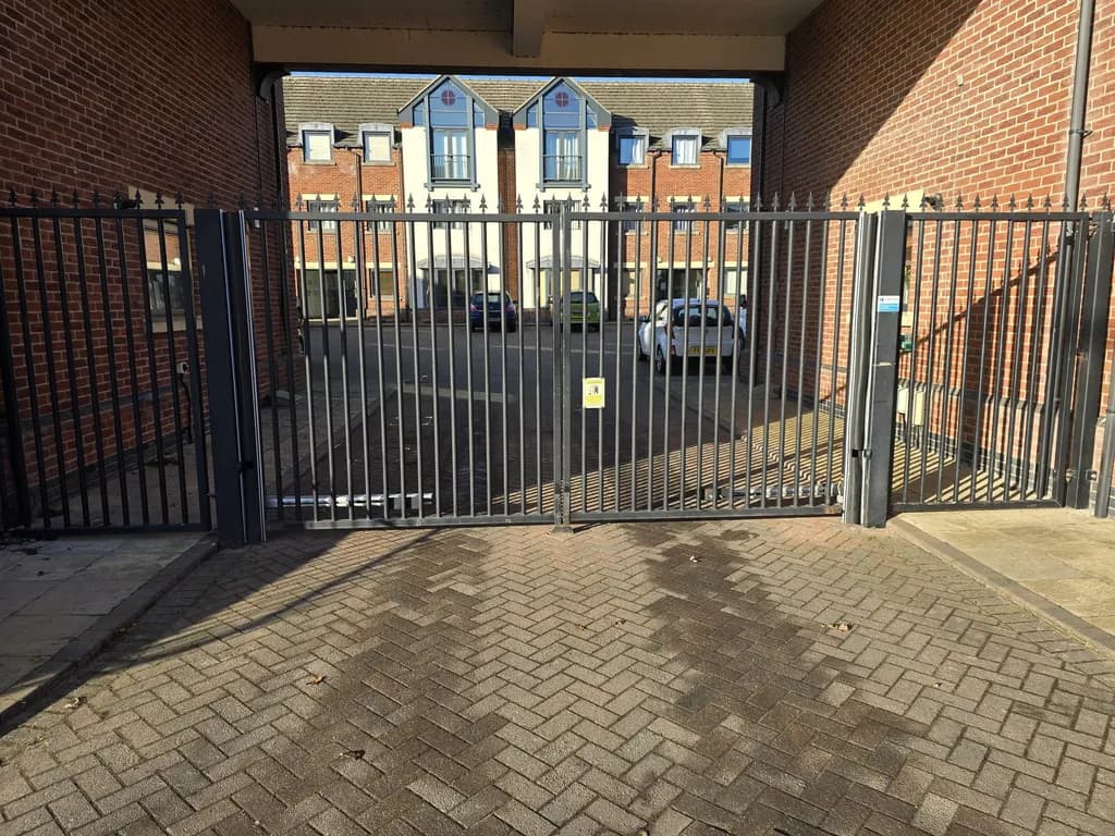 Tall bar gates under an archway at the entrance to an apartment courtyard