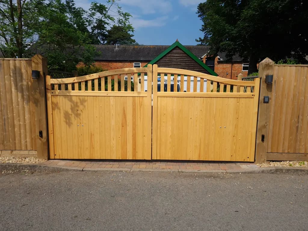 Curved-top timber gates with matching fence panels on a private driveway